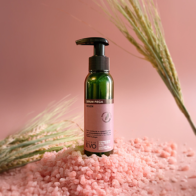 Immagine prodotto Serum Piega ambientata  su sfondo rosa decorata con foglie verdi e sale rosa 